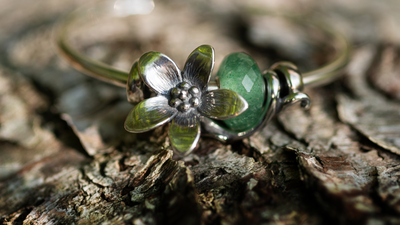 Flower bead in silver with a glass bead on a gold bangle