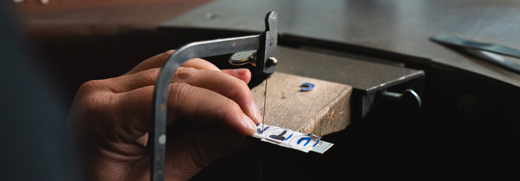 Letters being sawed in a silver plate with hand painted letters as a guide